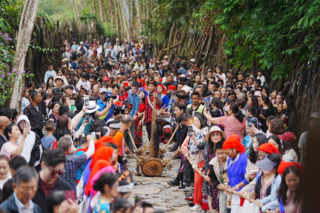 5月3日，各地游客在沧源县翁丁村和村民一起参加佤族传统民俗拉木鼓活动。（沧源县融媒体中心供图）