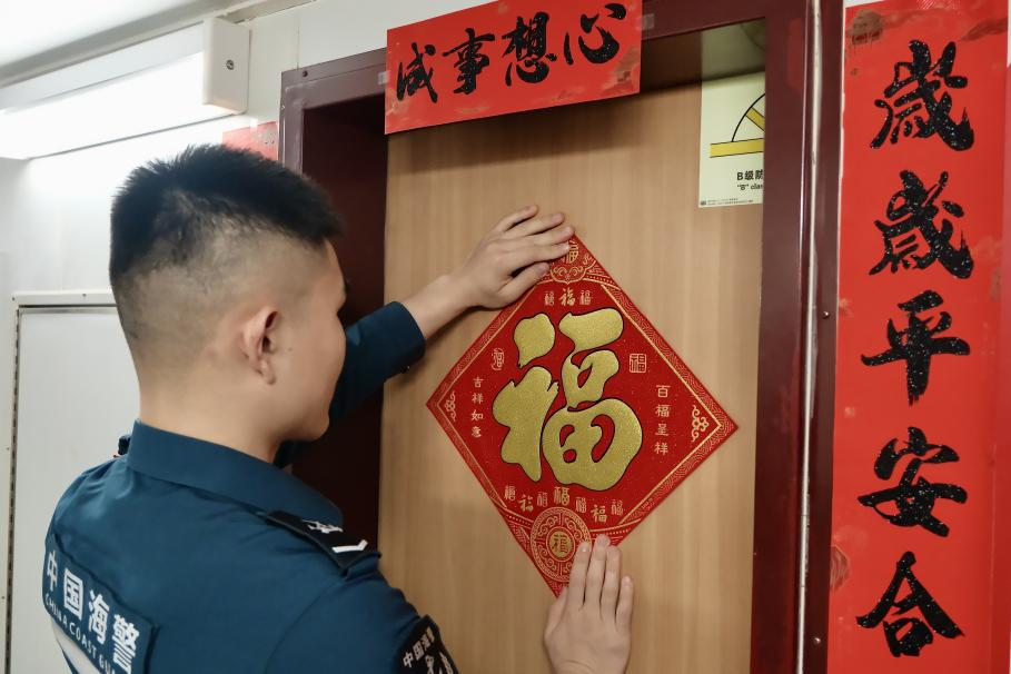 1月27日，在中国海警海鸥舰上，执法员贴春联福字庆祝农历春节。